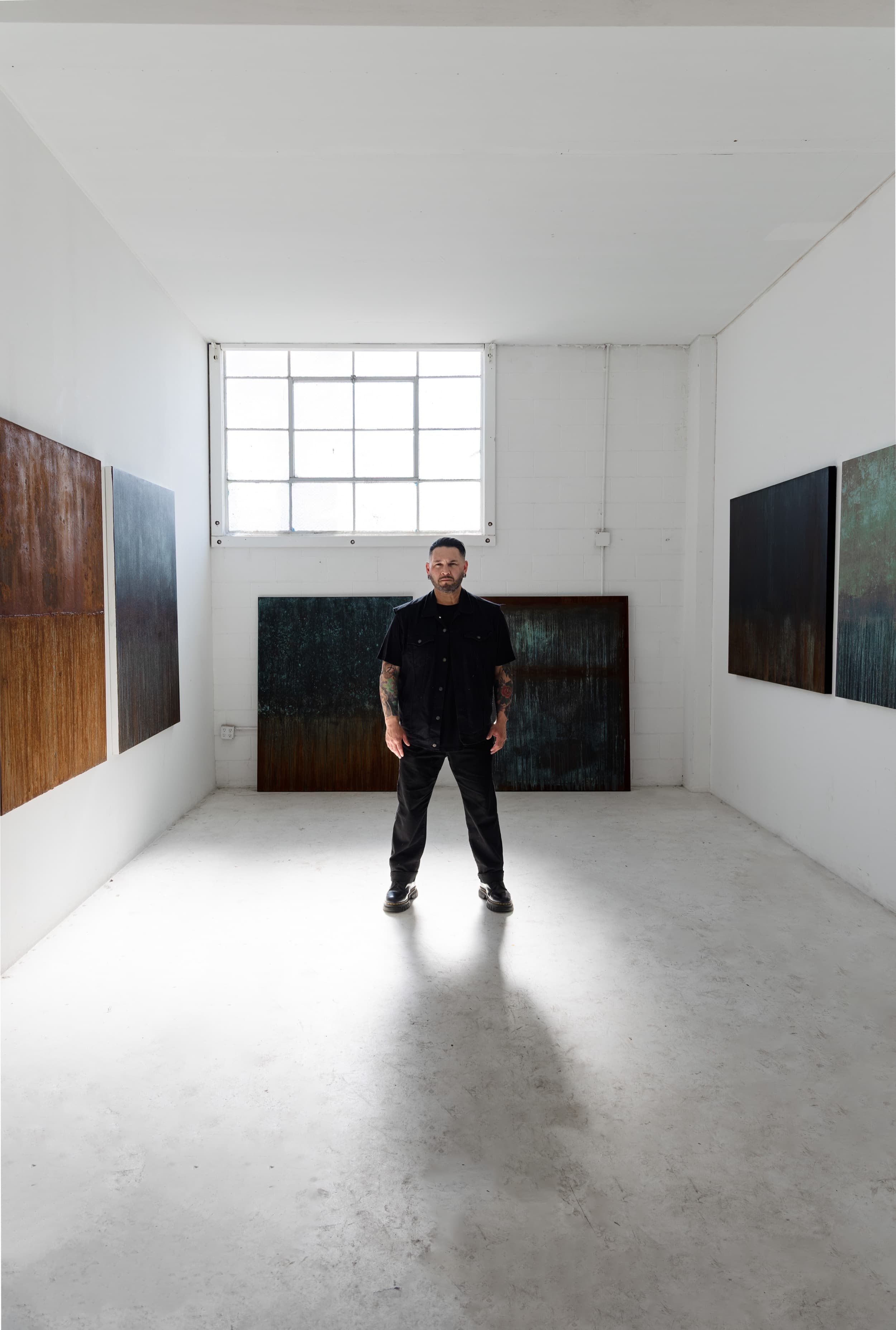 Danny R. Barragan standing in his studio with artworks